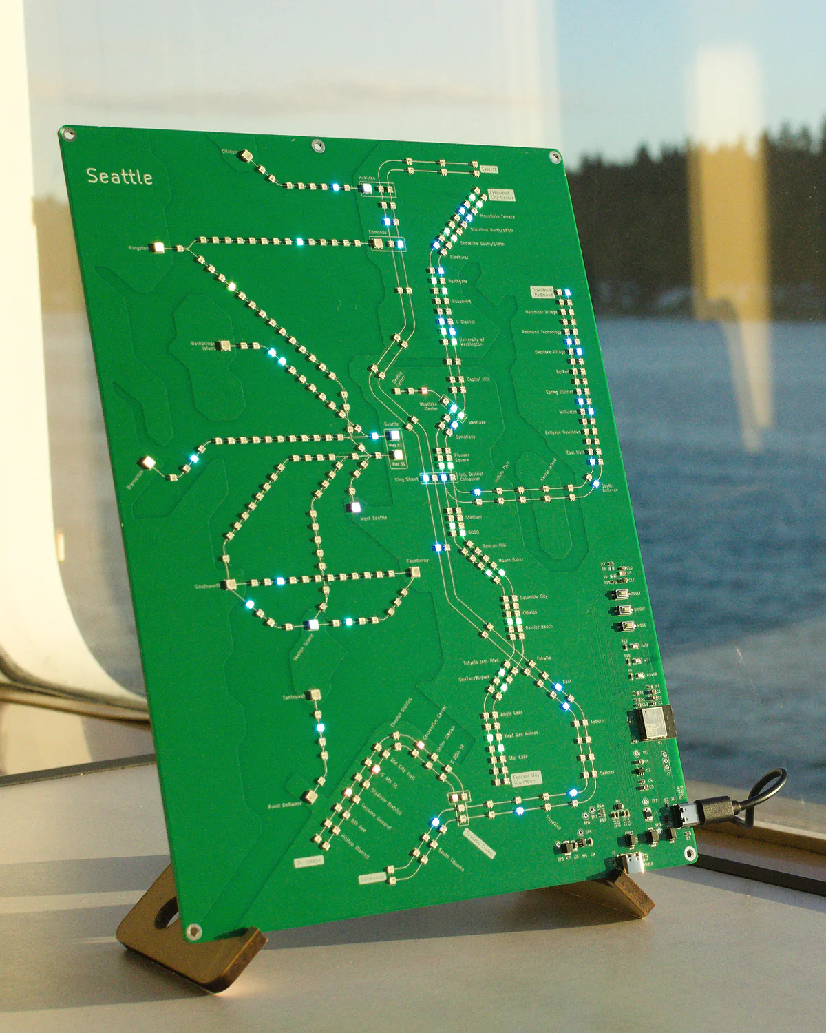 Seattle Transit Live illuminated beside a ferry window on Puget Sound
