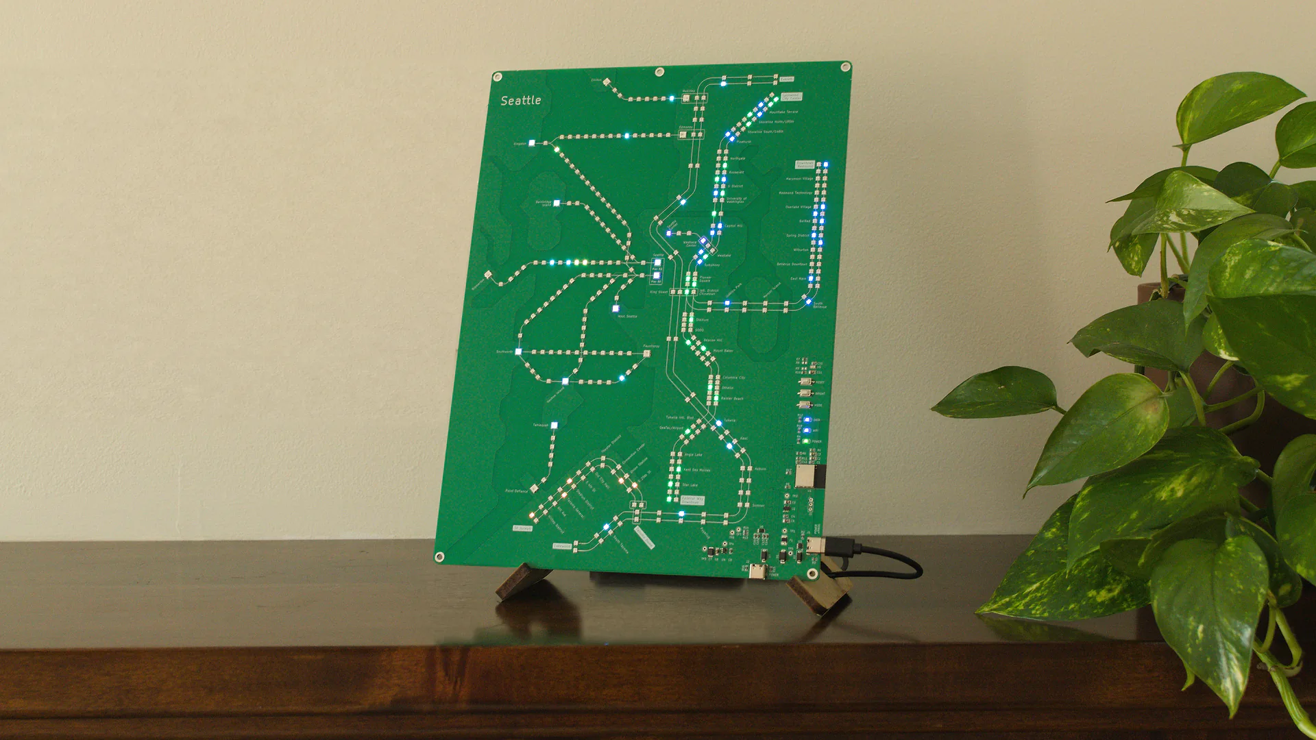 Seattle Transit Live illuminated on a shelf beside a houseplant